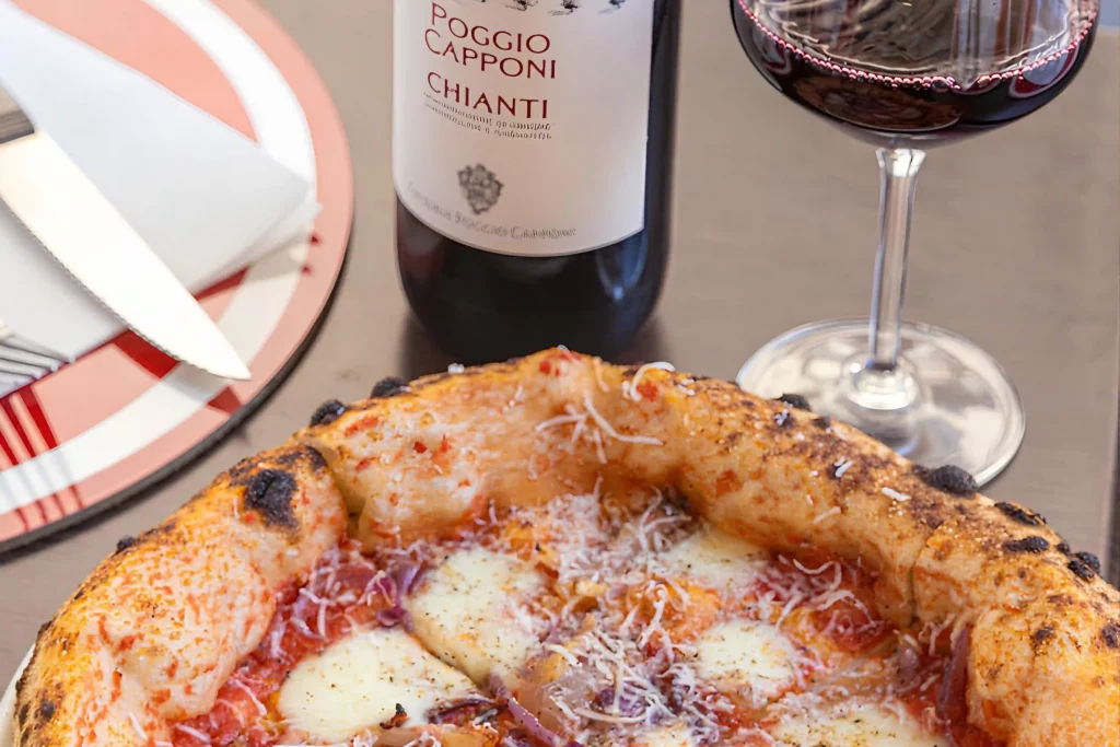 Pizza con mozzarella e pomodoro servita con bicchiere di vino rosso Chianti